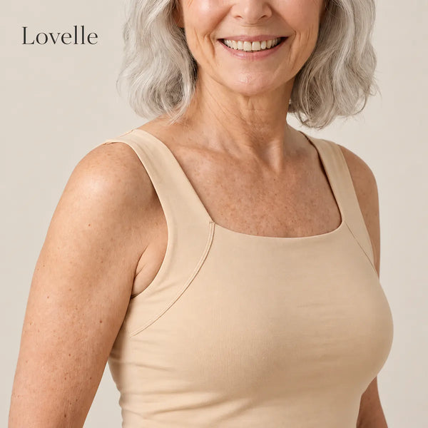 Donna sorridente dai capelli grigio argento con la canotta Lovelle Ease con reggiseno integrato, colore Nude, scollo quadrato e spalline larghe